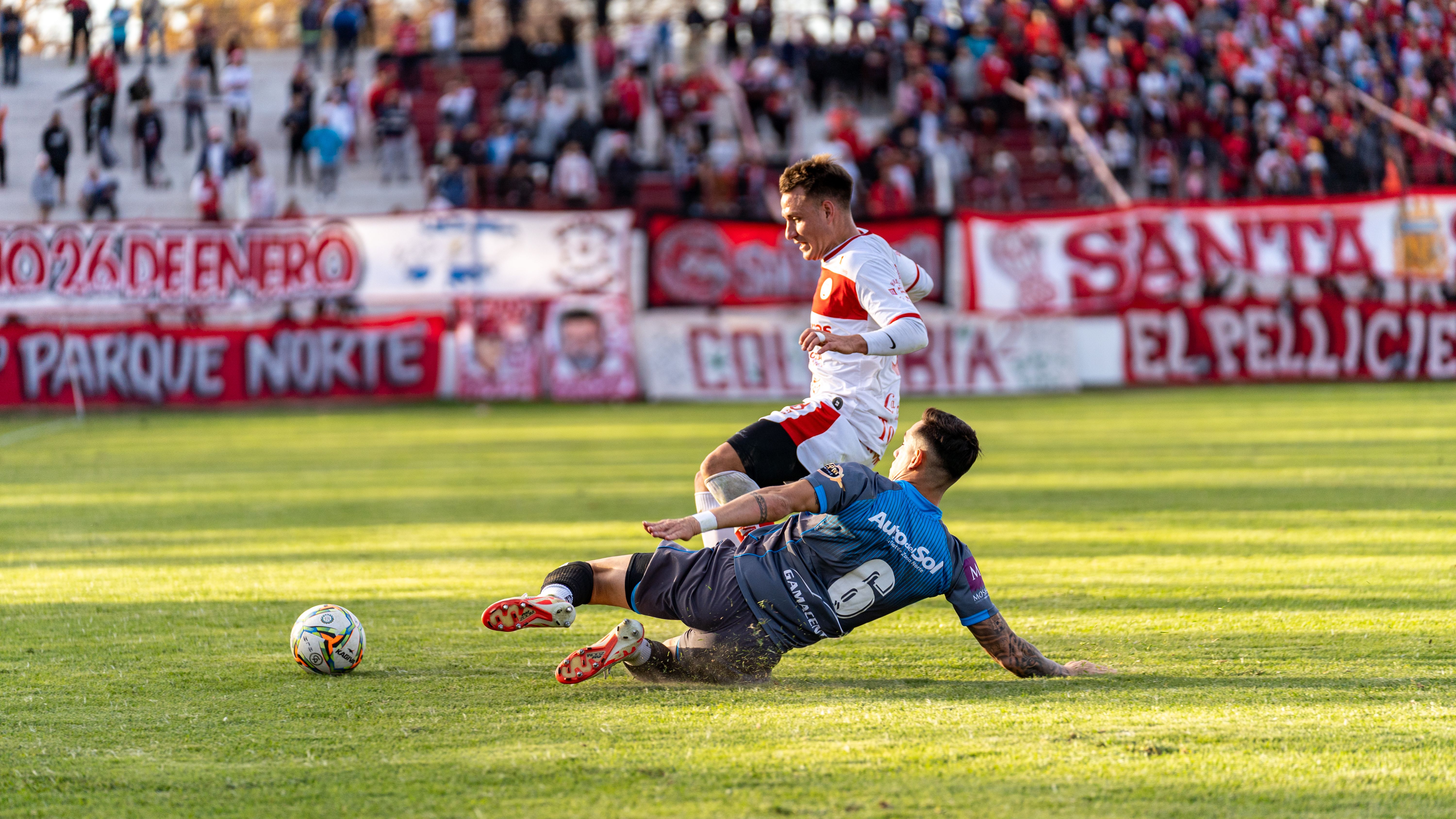 Two players contesting the ball with a sliding tackle